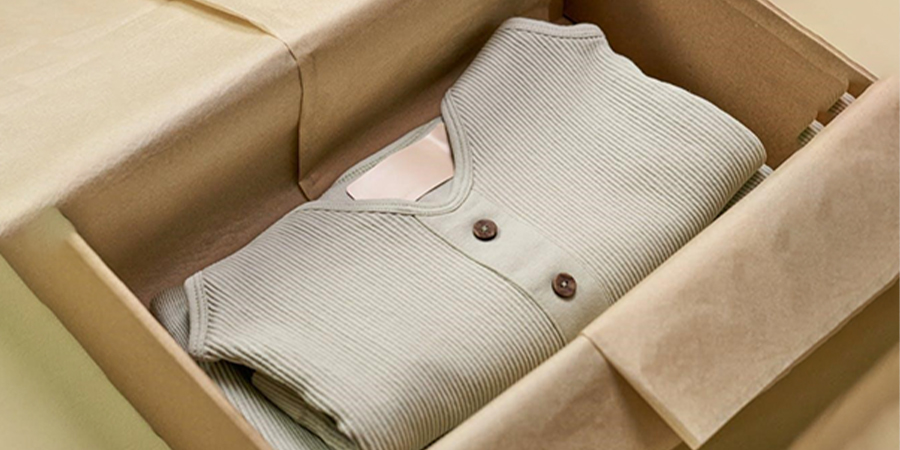 minimalist açık bej bir kutuda görüntülenen giysiler
