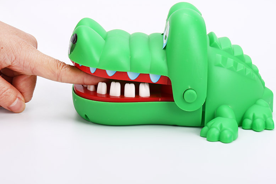 Ein Krokodilspielzeug, das sich in die Finger beißt, wenn es auf die Zähne drückt