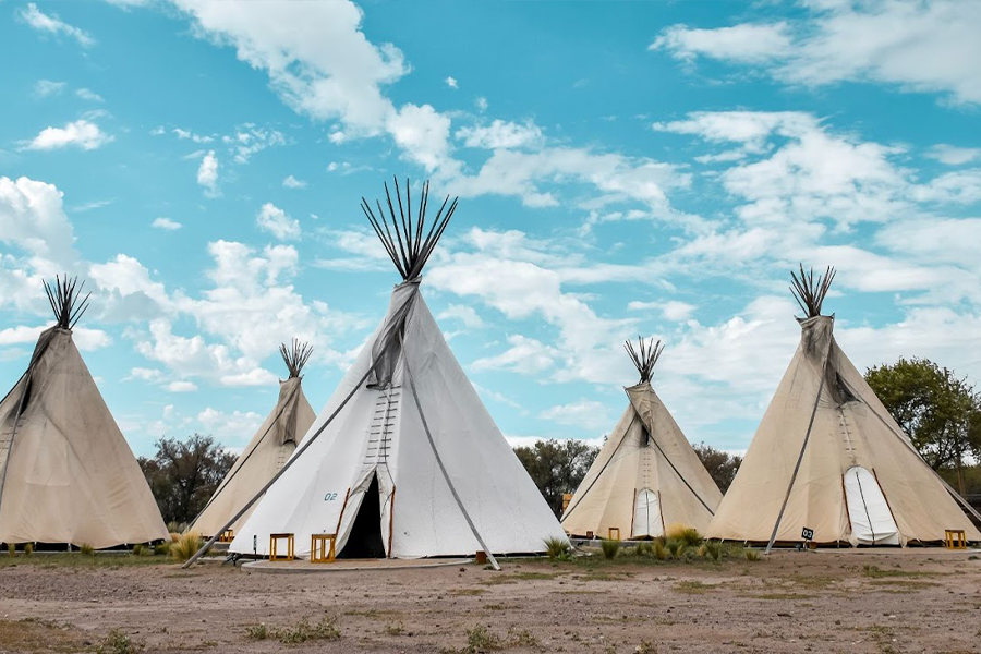 Five tipi tents on a muddy surface