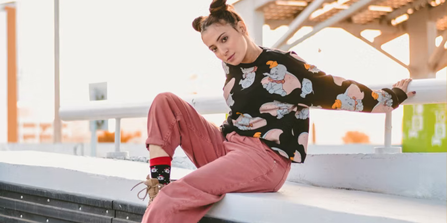 Woman posing in a cartoon printed top and candy-colored trousers