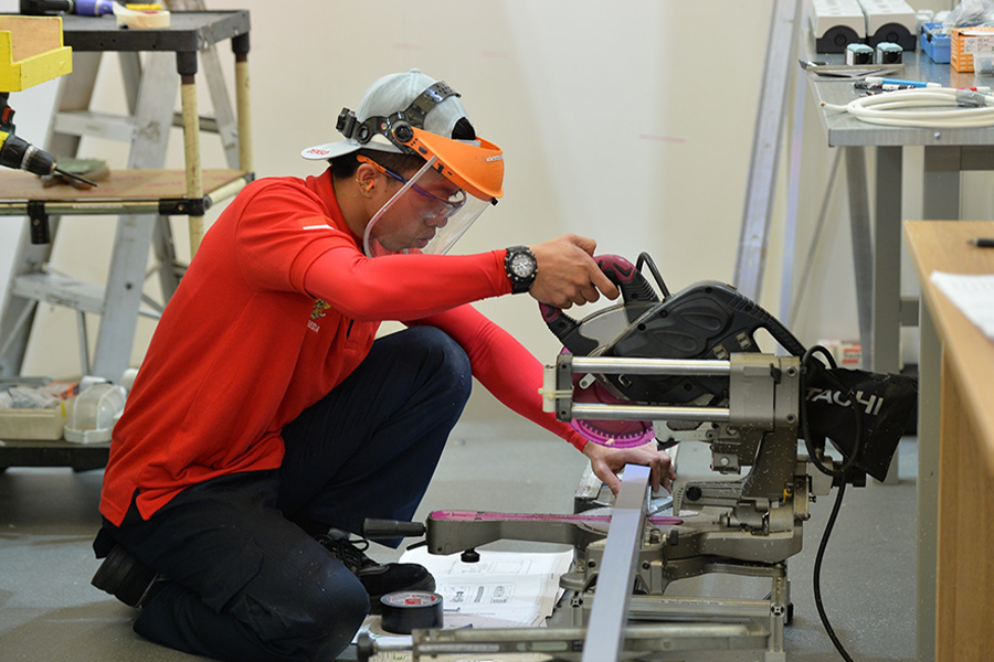 Man in red using table saw to cut wood