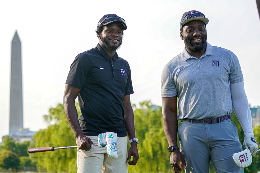 Two smiling men wearing hats and polo tees