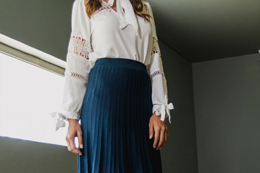 A woman wearing a blue midi skirt and white top