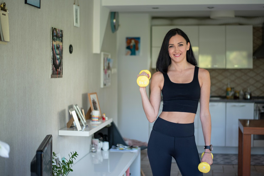 Lady wearing a black square-neck bra while holding two dumbbells