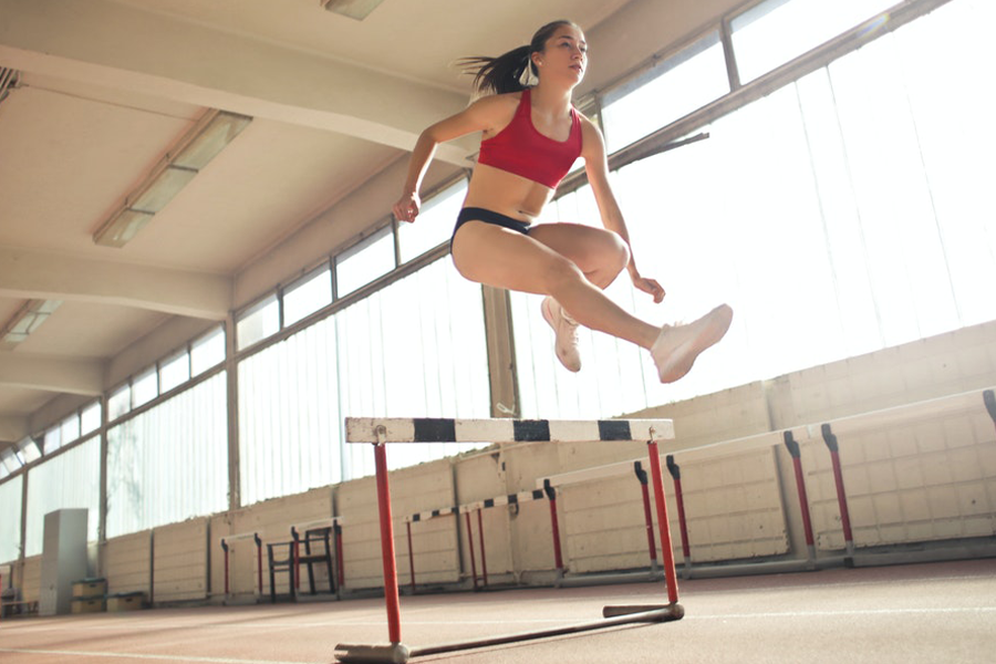 Woman jumping over an obstacle in a red square-neck bra