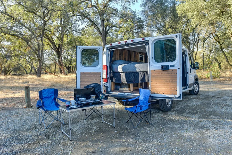 Blue folding camping chairs set up outside a campervan