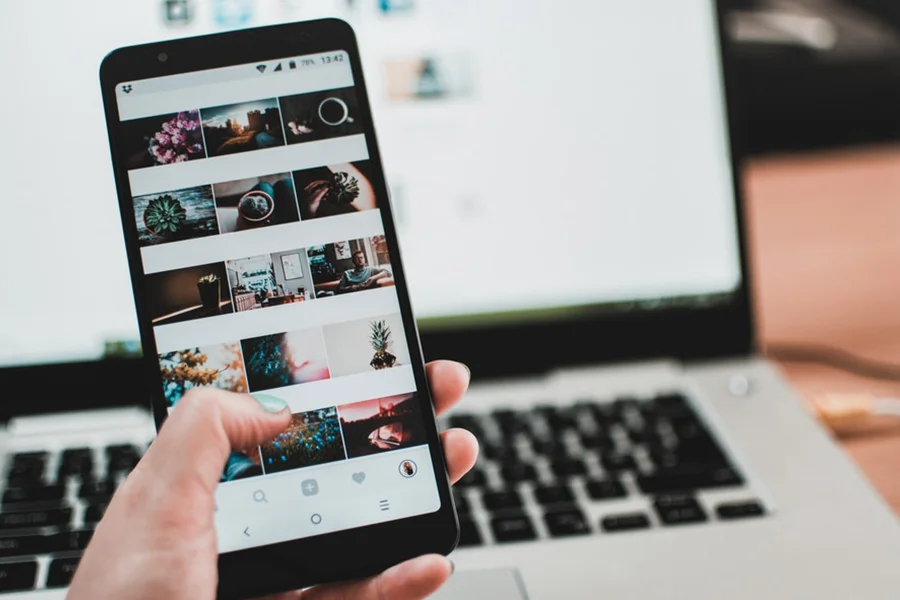 Female hand holding smartphone showing Facebook Reels