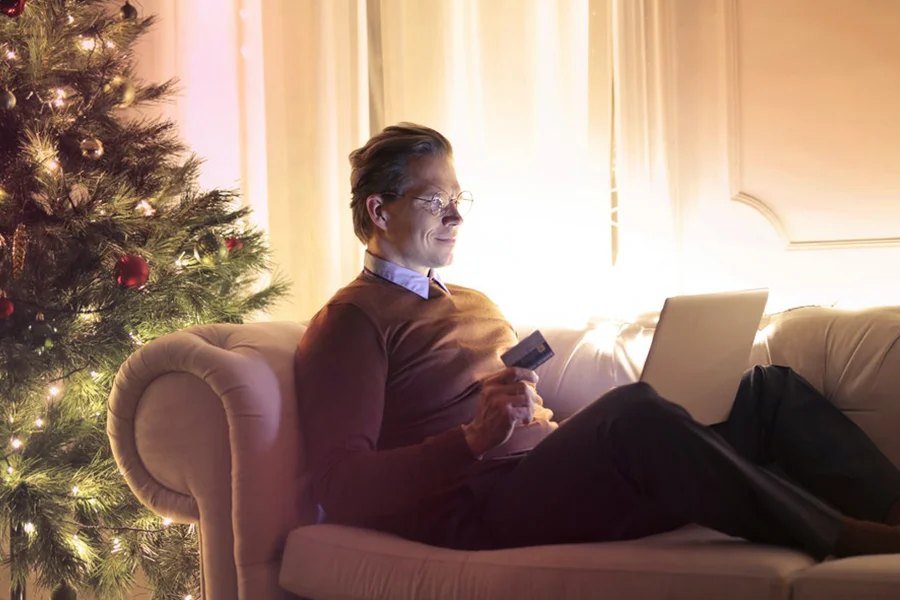 Man in brown sweater shopping online with card