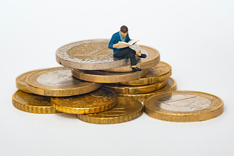 Toy man sitting on a bunch of coins