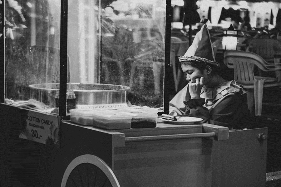 A young lady quietly looking at a cotton candy machine