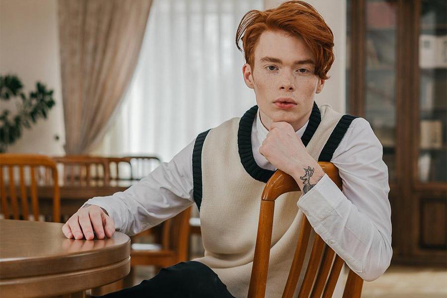 Man rocking cream-colored knitted vest over white long-sleeve