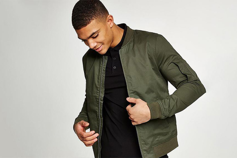 A man wearing a light green bomber jacket