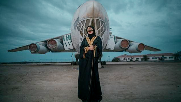 Uma mulher vestindo um Abaya preto na frente de um avião