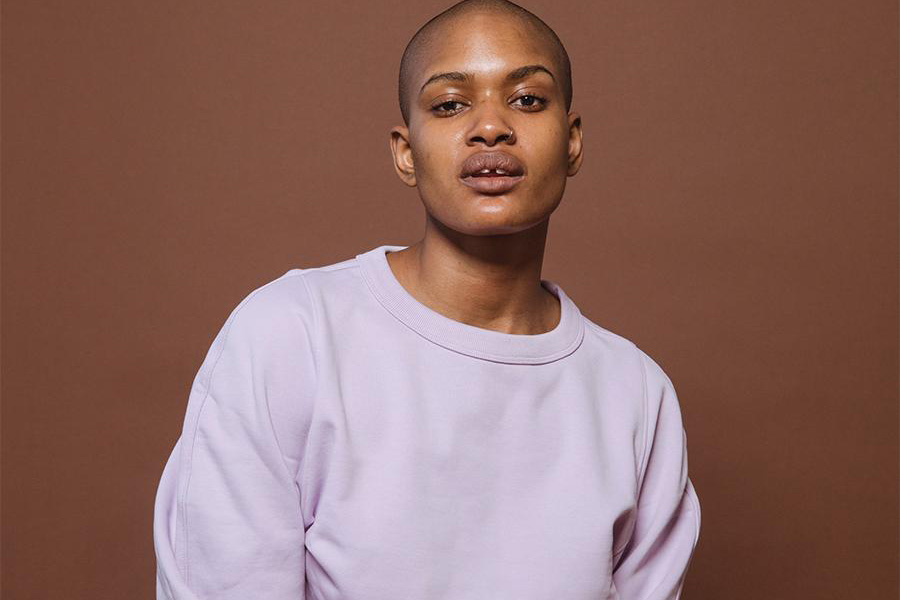 Lady wearing posing in a studio with a lavender top