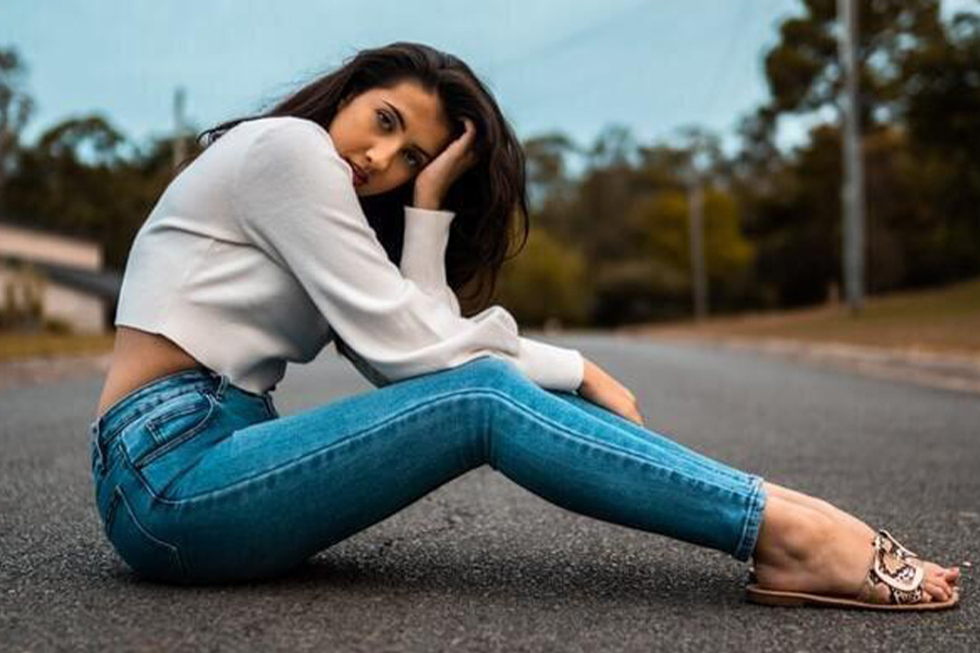 A woman sitting on the asphalt while wearing skinny jeans