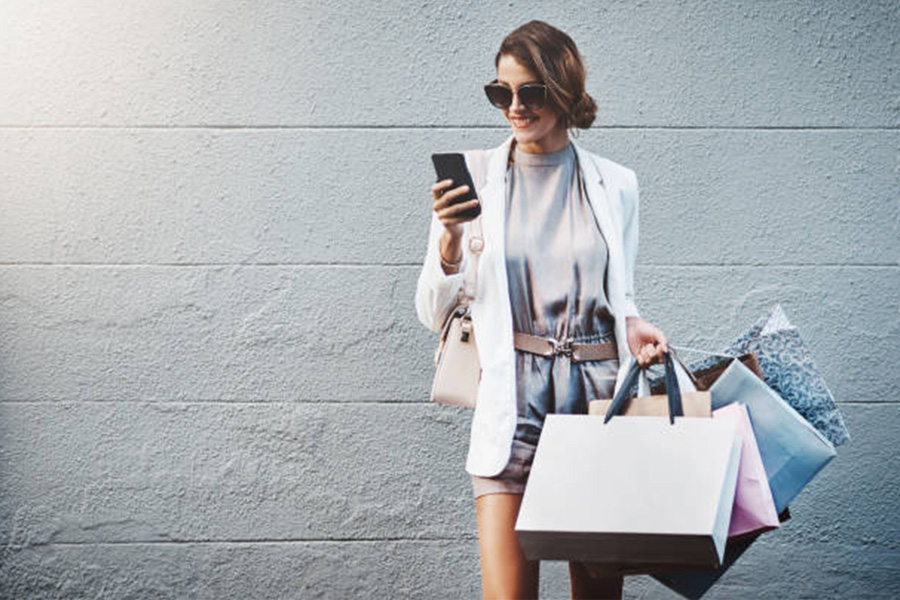 Woman texting while holding paper shopping bags in hand