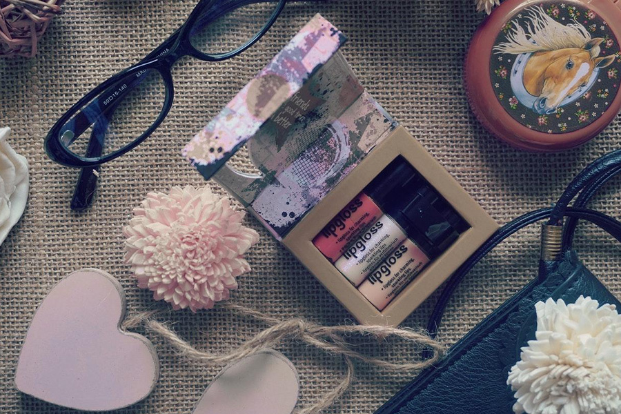 A set of lipgloss and sunglasses on a table