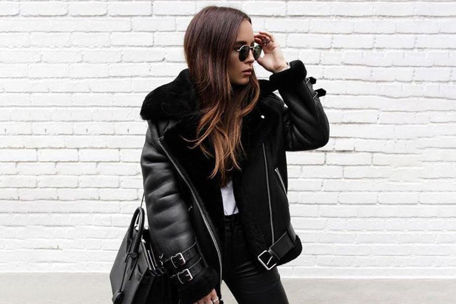 A woman in a glossy black leather jacket