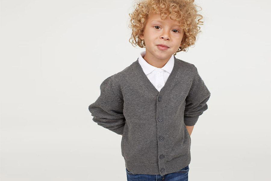 Boy with curly hair in a gray cardigan