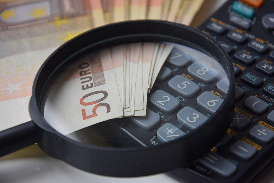 Magnifying glass and money papers next to a calculator