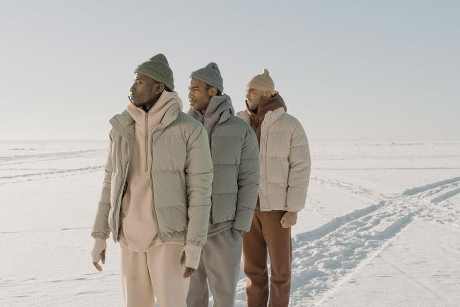 Three men wearing gray puffer jackets outdoors