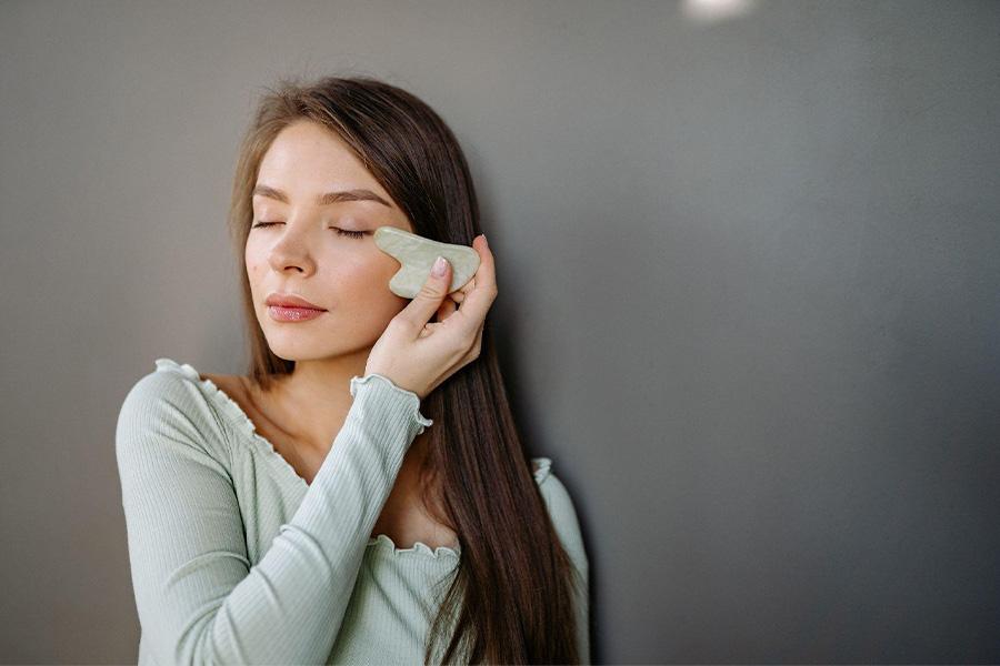 Woman massaging her face with a gua sha