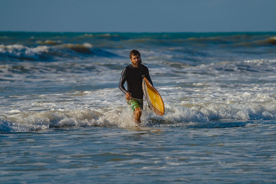 A man wearing a black rash top and swim trunks