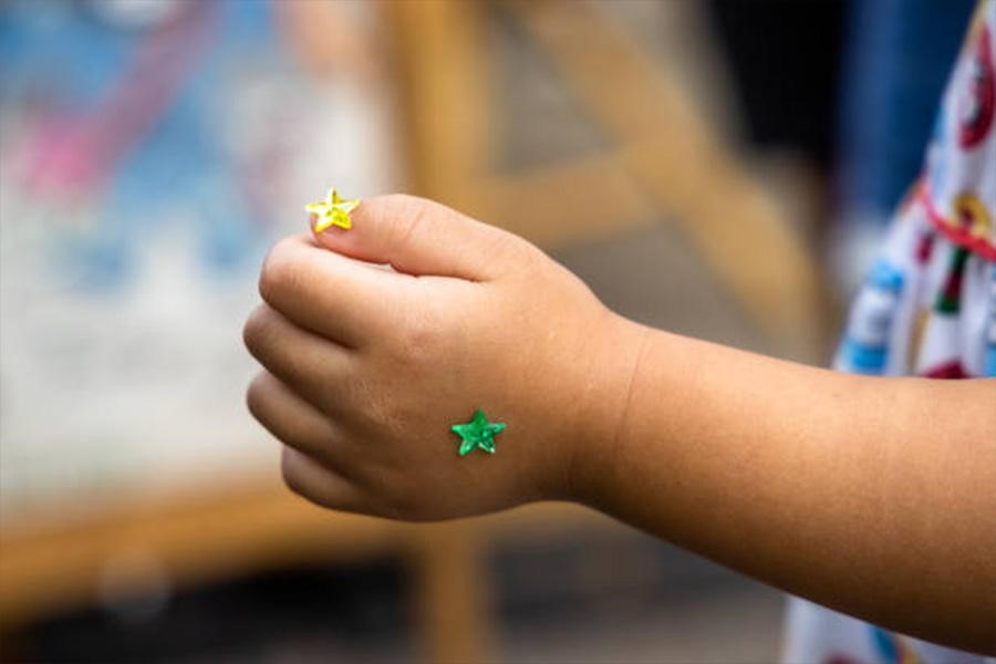 Child with two small shiny star stickers on hand