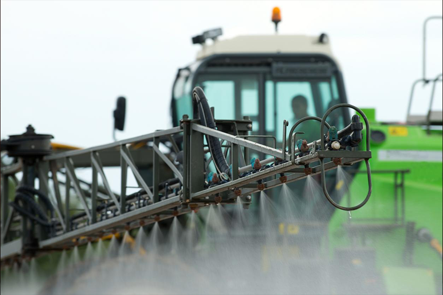 Crop sprayer spraying pesticides on crops in a field