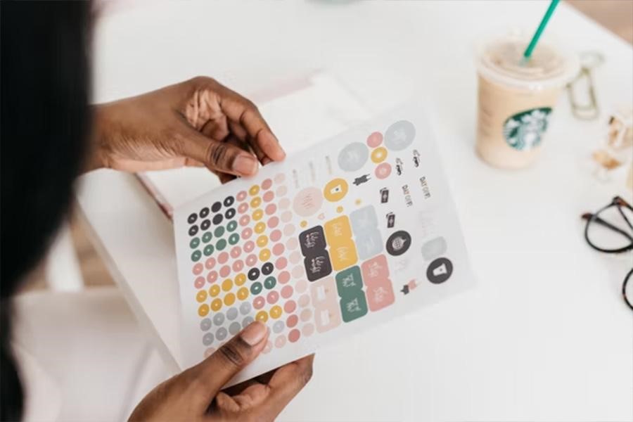 Person holding a sheet of pastel-colored stickers