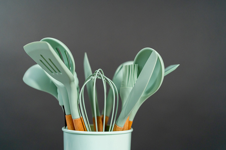 Silicone cooking utensils with wooden handles on black background