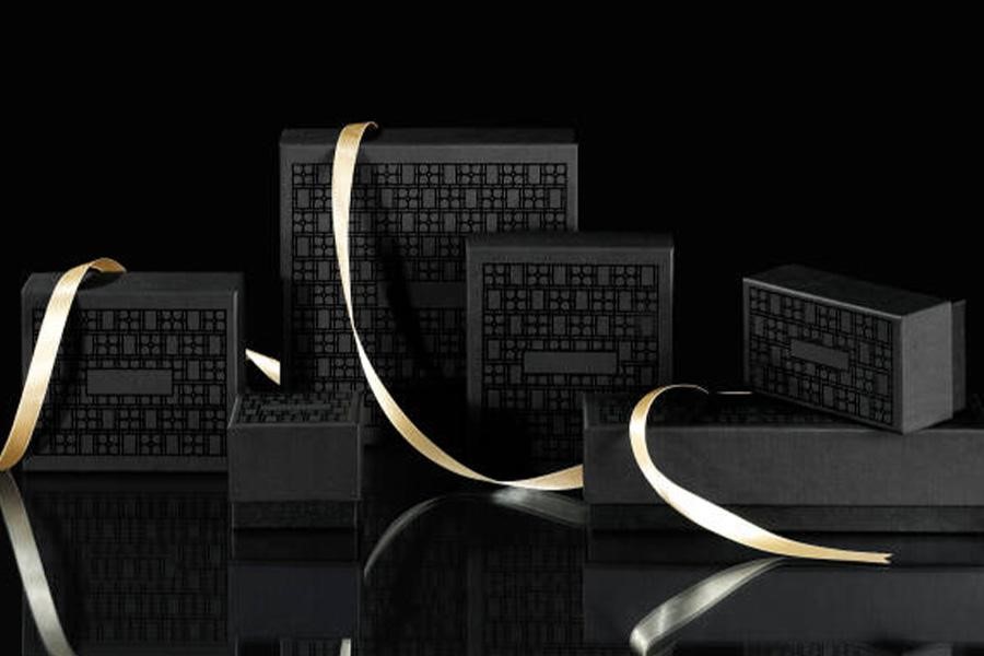 Various sizes of black shipping boxes with gold ribbon