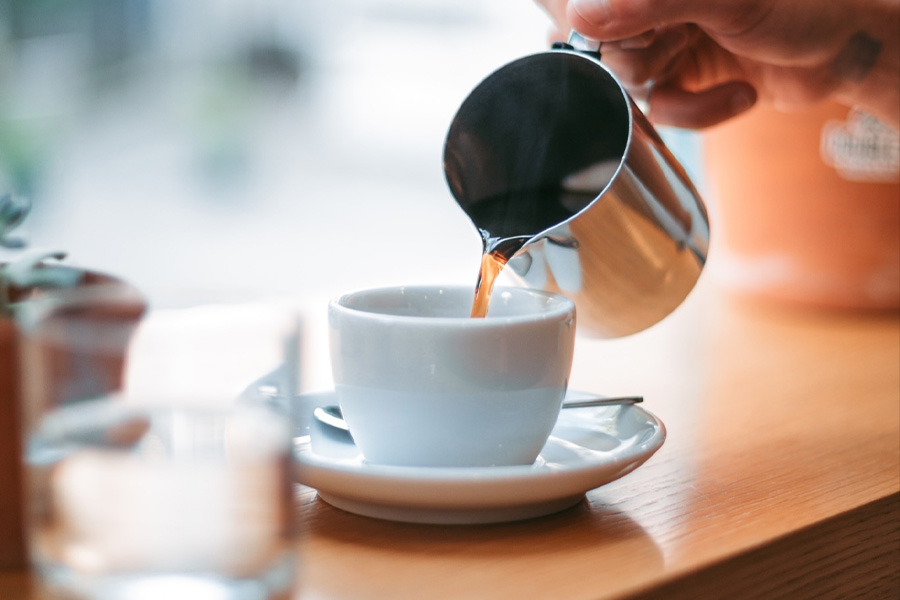 A hand pouring morning cup of coffee