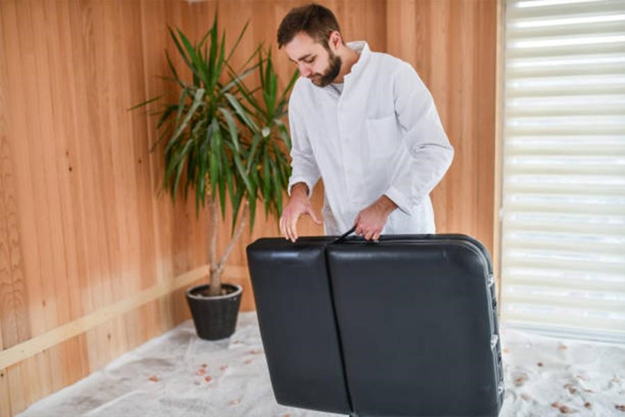 Black massage table being folded for easy transportation