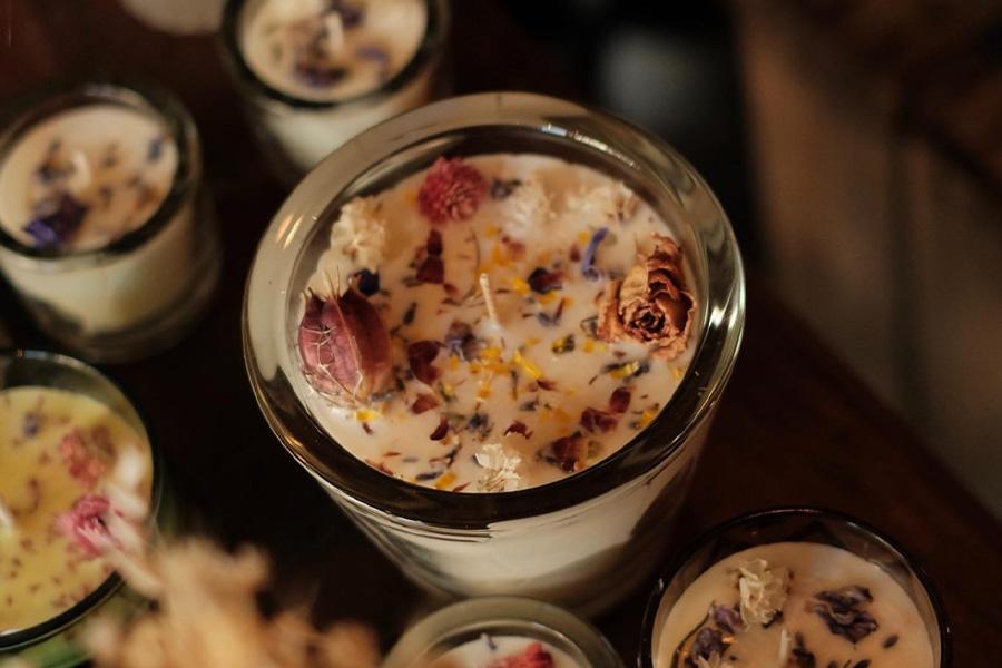 Candles with rose petals sit on a wooden countertop