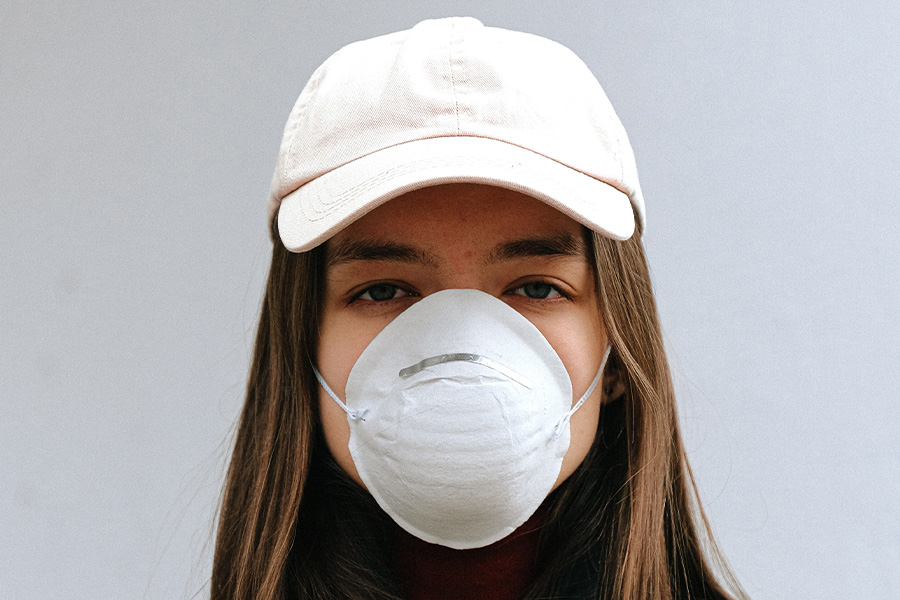 Masked woman wearing a white pre-curved baseball cap