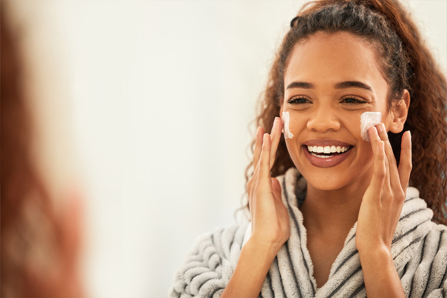 Smiling woman applying face cream