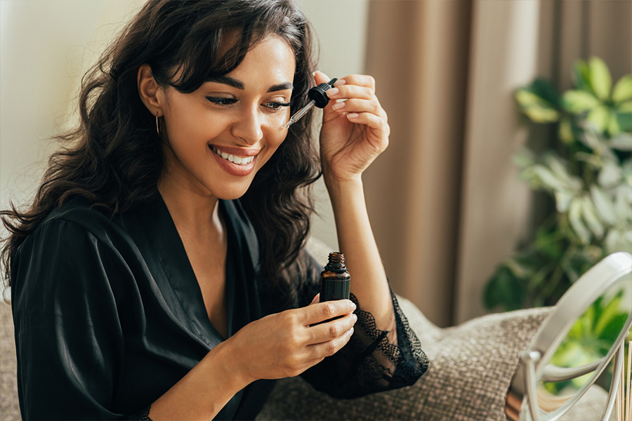 Smiling woman applying serum on her face