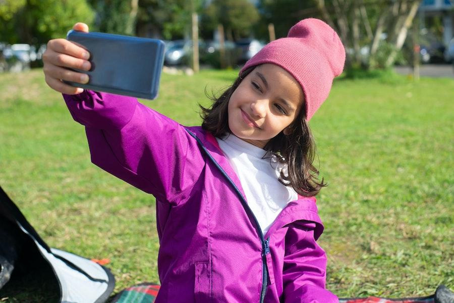 Tween smiling while taking a selfie outdoors