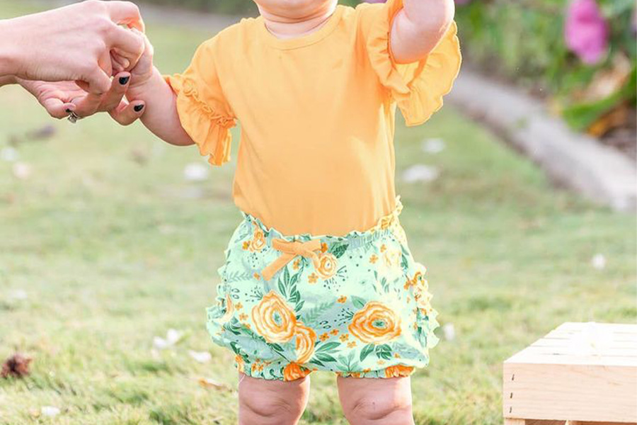 Woman holding baby wearing sweater shorts