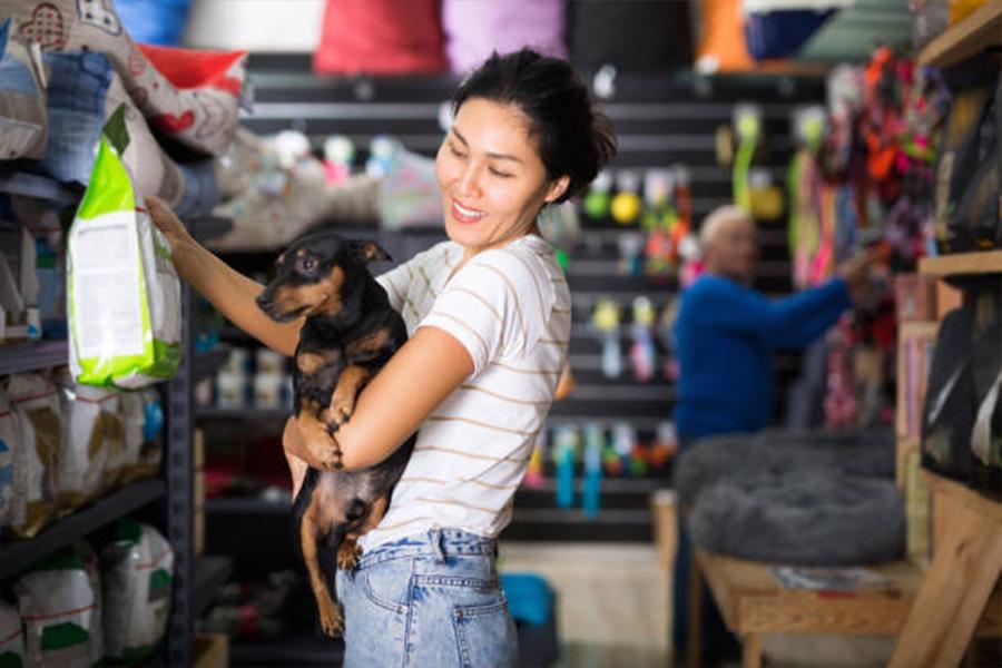 Woman with dog holding up large bag of dog food