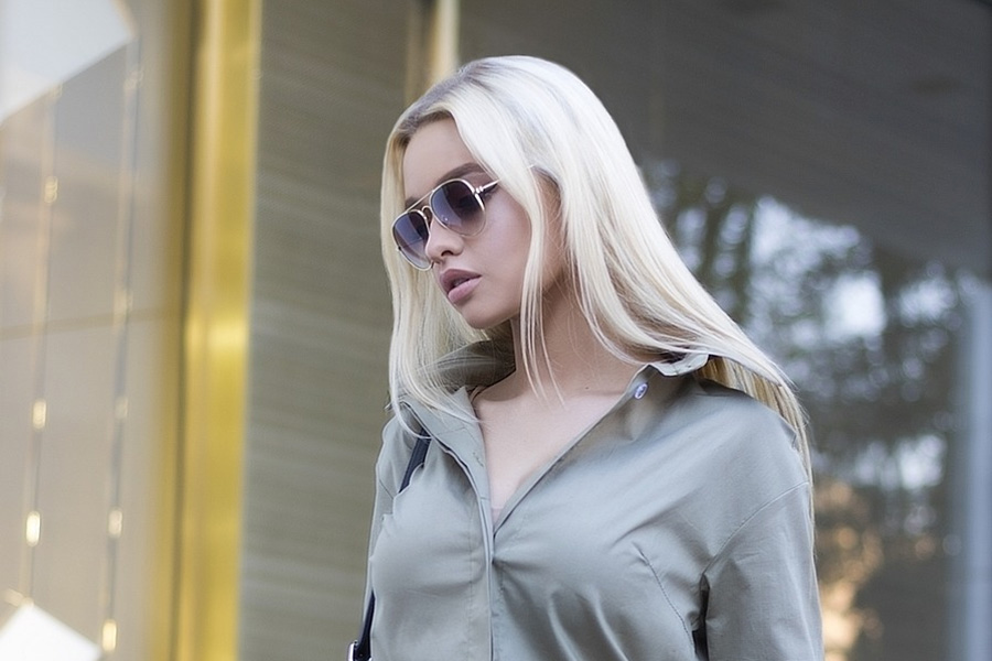 A lady walking down the street wearing loose top and blue pants