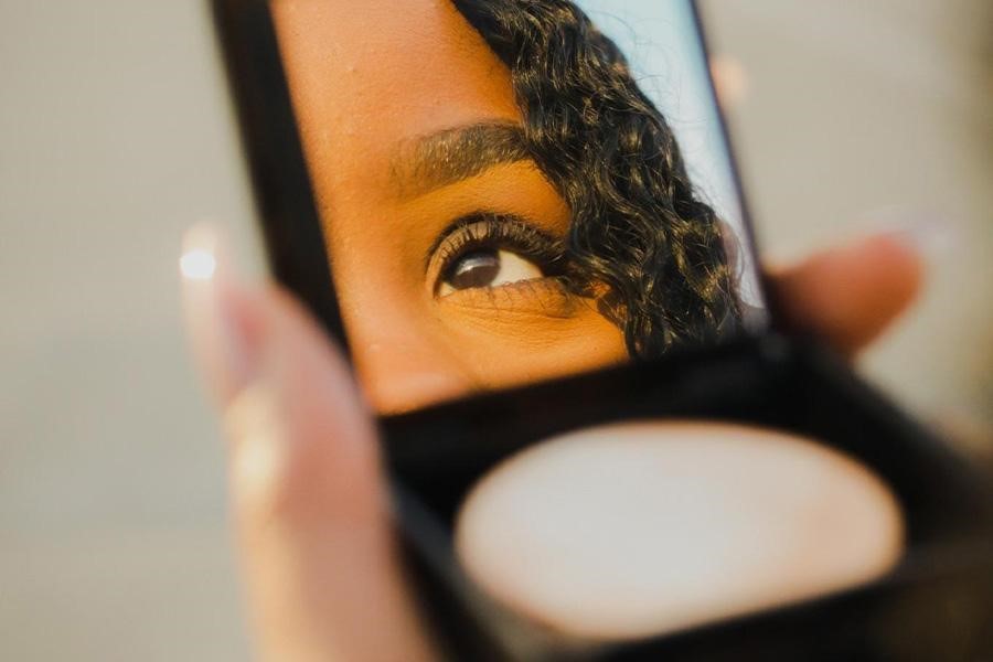 A person holding a small highlighter compact