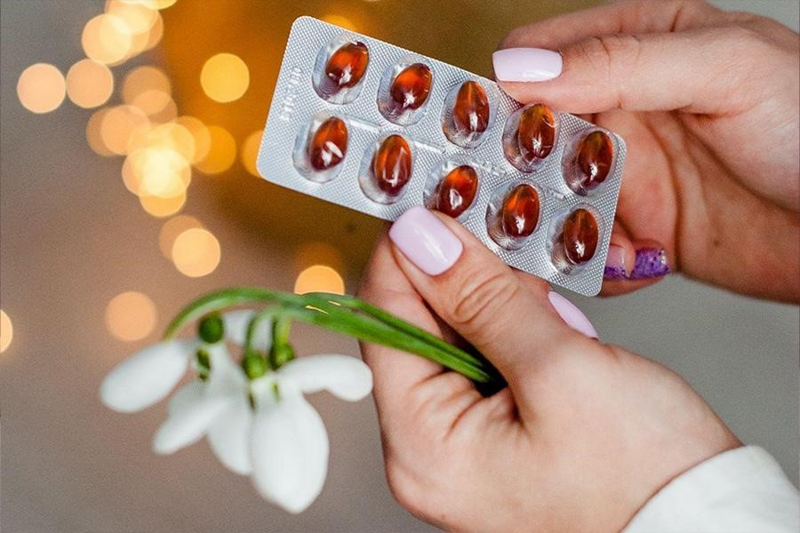 A woman holding red color capsules