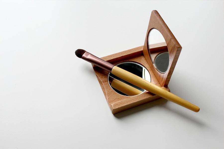 A wooden refillable blush/compact product sitting on a counter