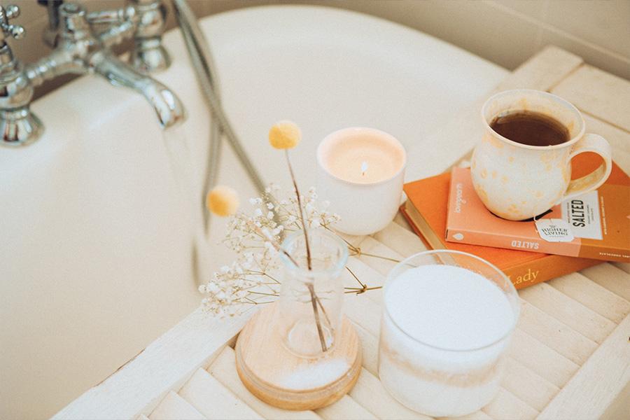 Flowers and candles on tray over bathtub