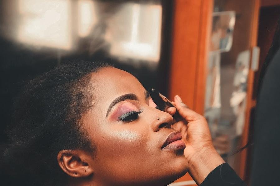 Lady applying colorful makeup on her face