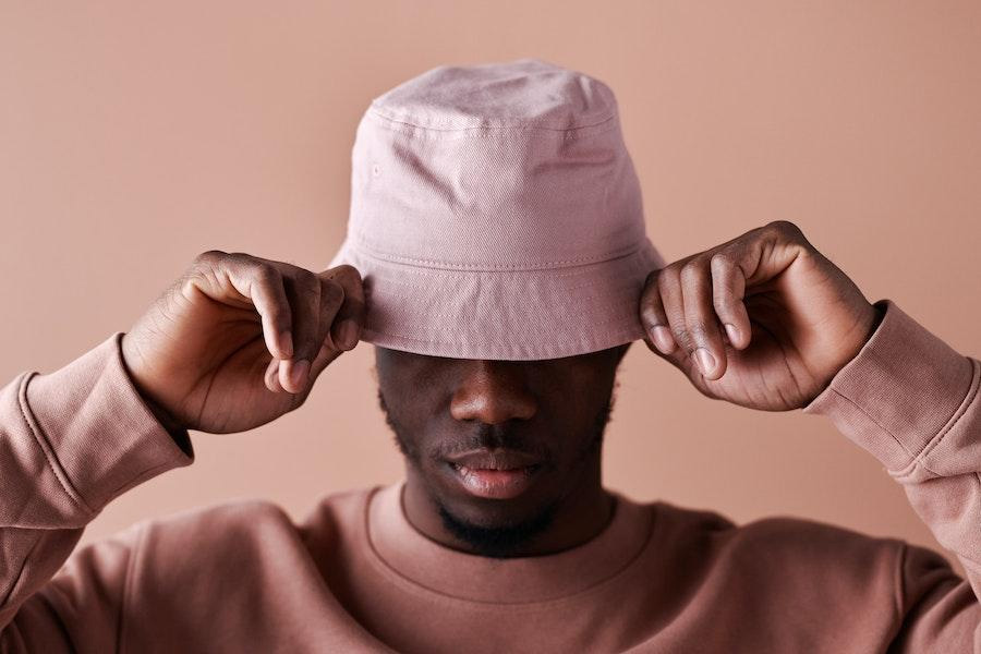 Man holding the brim of a pink bucket hat