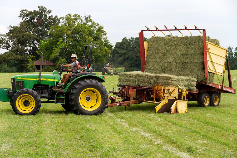 Man riding on riding mower carrying hays