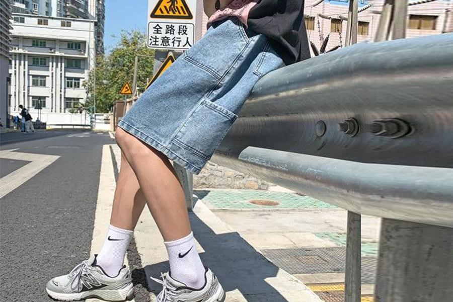 Man sitting on railings in denim cargo shorts